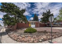 Charming brick home with a yellow front door, set back from the street with mature trees and landscaping at 1906 S Vrain St, Denver, CO 80219