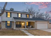 Charming two-story home with well-manicured lawn and covered front porch at dusk at 11861 E Yale Ct, Aurora, CO 80014