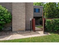 Brick exterior of unit 74, with a wooden gate leading to the front entrance and lush landscaping at 1233 S Yosemite Way # 74, Denver, CO 80247