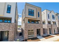 Modern townhome featuring a brick facade, neutral-toned siding, and contemporary window design on a sunny day at 11487 E Briarwood Cir, Centennial, CO 80112