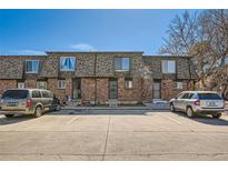 Three-unit townhouse exterior showing brick facade and parking spaces in front on a sunny day at 14462 E Mississippi Ave # B, Aurora, CO 80012