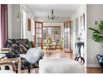 Open-concept living room featuring hardwood floors, a decorative chandelier, and bright dining area at 3308 S Birch St, Denver, CO 80222