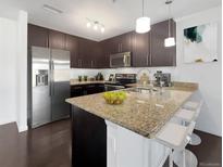 This kitchen features sleek, dark cabinetry, stainless steel appliances, and granite countertops with a breakfast bar at 1062 Rockhurst Dr # 302, Highlands Ranch, CO 80129