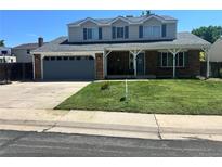 Charming two-story home with a well-manicured lawn, attached garage, and inviting front porch at 12528 Ash St, Thornton, CO 80241