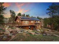 Charming cabin-style home with a large deck, solar panels, and a beautiful wooded surrounding at 11398 Ranch Elsie Rd, Golden, CO 80403