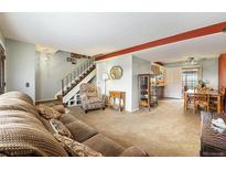 Inviting living room featuring neutral carpet, a plush sofa, and easy access to the dining area and staircase at 628 S Carr St, Lakewood, CO 80226