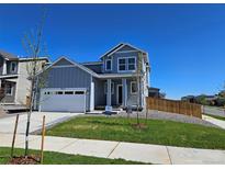 Charming two-story home featuring a well-maintained lawn, a two-car garage, and a welcoming entrance at 6077 Idlewild Pl, Brighton, CO 80601