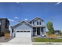 Charming two-story home with a two-car garage, covered porch, and manicured lawn at 6077 Idlewild Pl, Brighton, CO 80601