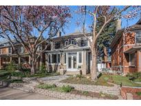Charming two-story home featuring a lovely landscaped front yard with blooming trees and a stone walkway at 1419 N Adams St, Denver, CO 80206