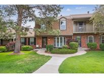 Charming townhome featuring a brick facade, well-manicured landscaping, and inviting walkway at 8981 E Amherst Dr # E, Denver, CO 80231