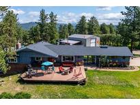 Charming single-story home featuring an expansive deck with outdoor seating, perfect for entertaining and relaxation at 29263 Sue Rd, Evergreen, CO 80439