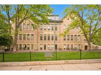 Beautiful brick multi-Gathering building with green space enclosed with black wrought iron fencing and mature trees at 1140 Columbine St # 106, Denver, CO 80206