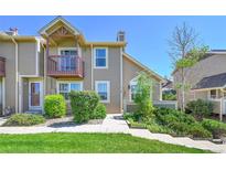 Two-story townhouse with tan siding, second story balcony, mature landscaping, and walkway at 4146 S Mobile Cir # A, Aurora, CO 80013