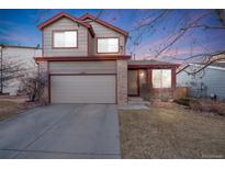 Charming home featuring neutral siding, brick accents, two-car garage, and a well-maintained lawn at 11207 Tumbleweed Way, Parker, CO 80138