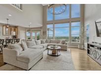 Bright living room with large windows, plush seating, and modern chandelier with hardwood flooring and scenic views at 12059 S Tallkid Ct, Parker, CO 80138