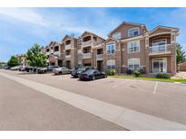 Apartment building featuring stone accents, balconies, and ample parking at 7440 S Blackhawk St # 2-104, Englewood, CO 80112