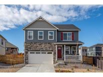 Charming two-story home with a stone facade, white garage door, and red front door at 27664 E Byers Ave, Aurora, CO 80018