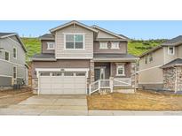 Charming two-story home featuring stone accents, neutral siding, a two-car garage, and a welcoming front porch at 7357 S Yank Ct, Littleton, CO 80127
