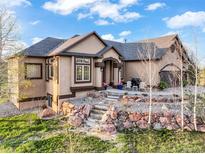 Beautiful home featuring a stylish entryway, rock landscaping, and a neutral stucco exterior at 1236 Castlecombe Ln, Monument, CO 80132