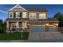 Charming two-story home with a stone facade, manicured lawn, and a three-car garage at 7083 Winthrop Cir, Castle Rock, CO 80104