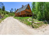 Charming A-frame cabin with a large deck surrounded by lush greenery and a winding driveway at 422 Fairview Blvd, Breckenridge, CO 80424