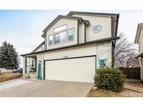 Two-story home with a two-car garage and light beige siding. A well-kept bush is at the side of the garage at 11997 W Coal Mine Dr, Littleton, CO 80127