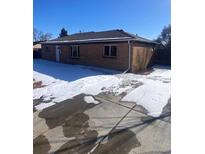 Ranch style home with a large yard and driveway, partially covered in snow at 1240 Russell Blvd, Thornton, CO 80229