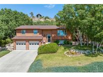 Charming two-story home featuring a well-manicured lawn, mature trees, and a two-car garage at 452 Gordon Dr, Castle Rock, CO 80104