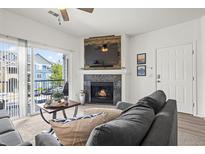 Inviting living room with a fireplace and mounted television, with light-filled balcony access at 4451 S Ammons St # 4-203, Littleton, CO 80123