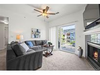 Bright living room features a ceiling fan, balcony access, and comfortable gray couches at 4451 S Ammons St # 4-203, Littleton, CO 80123