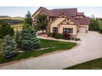 Beautiful exterior elevation with a well manicured lawn, mature trees and a long driveway at 19735 Knights Xing, Monument, CO 80132