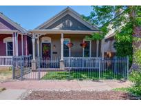Charming home featuring a manicured lawn, a decorative fence, and hanging floral arrangements at 2941 Glenarm Pl, Denver, CO 80205