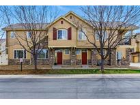 Inviting townhomes with stone accents, red doors, bare trees, and well-maintained landscaping create a charming curb appeal at 9980 W Jewell Ave # B, Lakewood, CO 80232