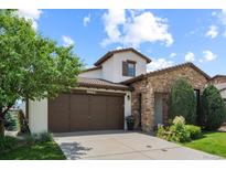 Charming stucco and stone home with a well-manicured lawn and a brown two-car garage door at 15290 W Baker Ave, Lakewood, CO 80228
