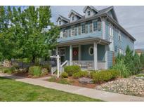 Two-story home with blue siding, front porch, and landscaping at 9075 E 36Th Ave, Denver, CO 80238