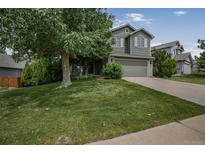 Charming two-story home with a well-manicured lawn and mature shade tree in a suburban neighborhood at 611 Branding Iron Ln, Castle Rock, CO 80104