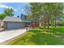 Charming two-story home with brick and siding, a well-manicured lawn, mature trees, and an attached two-car garage at 4390 S Sheridan Blvd, Littleton, CO 80123