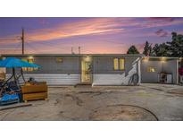 Charming single-story home featuring a concrete yard, covered parking, and a warm, inviting exterior under a colorful evening sky at 481 Cragmore St, Denver, CO 80221