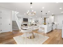 Open-concept living space featuring a dining area, modern chandelier, and elegant decor, with wood floors at 8028 Williams Fork Ave, Littleton, CO 80125