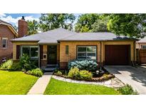 Charming brick home featuring a well-manicured lawn and colorful landscaping at 1635 Poplar St, Denver, CO 80220