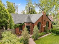 Charming brick home with a turret-style entry, arched windows, and lush landscaping at 1226 Dexter St, Denver, CO 80220