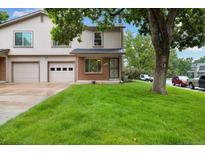 Traditional home featuring a well-manicured lawn and an attached two-car garage in a tranquil neighborhood at 1765 S Kline Way, Lakewood, CO 80232