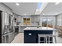 Modern kitchen boasts stainless steel appliances, stylish backsplash, island with seating and a skylight at 2894 S Jay St, Denver, CO 80227