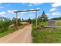 Welcoming ranch entrance with stone signage, a gated drive, and picturesque views of the property at 1380 Oak Valley Rd, Sedalia, CO 80135