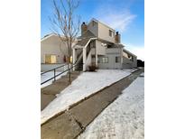 Exterior view of a two-story condo with stairs and snow-covered walkway at 17054 E Tennessee Dr # 212, Aurora, CO 80017