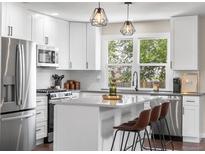 Modern kitchen with white cabinets, stainless steel appliances, and a stylish island with seating at 9220 Yucca Way, Thornton, CO 80229