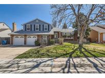 Charming two-story home with a well-manicured lawn, a two-car garage, and a classic brick facade at 10106 W Geddes Cir, Littleton, CO 80127