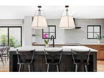 Bright kitchen features modern light fixtures, a white countertop island with black chairs, and stainless steel appliances at 121 S Ivy St, Denver, CO 80224