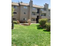 Exterior view of a condo building with landscaping and a pond at 3100 S Federal Blvd # 203, Denver, CO 80236