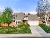 Charming gray home featuring a manicured lawn, mature trees, and a convenient two-car garage at 3706 E Easter Dr, Centennial, CO 80122